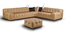 a tan leather couch and ottoman with black pillows