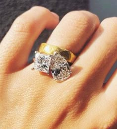 a woman's hand with two diamond rings on top of her finger and the other hand holding an engagement ring