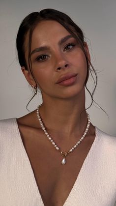 a woman wearing a necklace with pearls on it