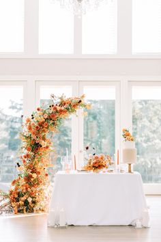 the table is set with an arch of flowers and candles, along with a cake