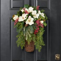 a basket filled with flowers hanging on the front door's black painted paneled door