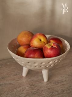 a white bowl filled with red and yellow apples