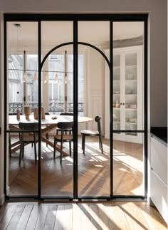 an open glass door leading to a dining room with wooden floors and white walls, along with a black framed sign that reads every picture i see with an arch in it