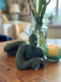 a statue sitting on top of a wooden table next to a vase filled with flowers