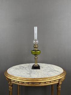 a table with a marble top and two candles on the base, sitting against a gray wall