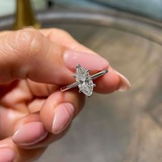 a woman's hand holding a diamond ring with the word tass written on it