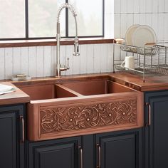 a kitchen sink with an intricate design on the front and side, in dark wood cabinets