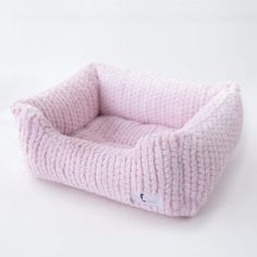 a pink knitted dog bed on a white background