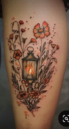 a woman's thigh with flowers and a lantern on it