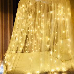 a bed covered in white netting with lights on it