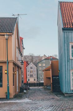 a cobblestone street lined with colorful wooden houses and small buildings on either side