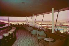 the inside of a restaurant with tables and chairs overlooking a large pool in the distance