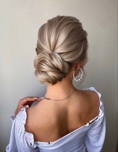 a woman with blonde hair in a low bun updo and pearls on her necklace