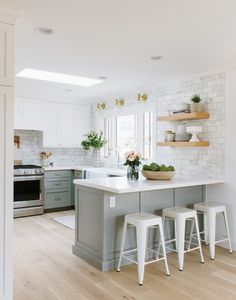 a kitchen with white and gray cabinets, counter tops, and stools in it