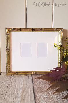 a white and gold frame sitting on top of a wooden table next to a potted plant