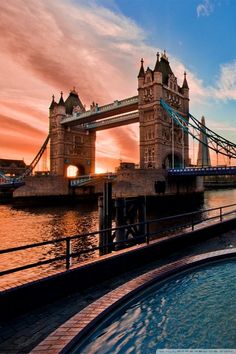 the sun is setting over tower bridge in london