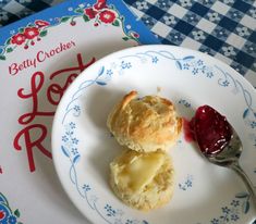 two biscuits on a plate next to a spoon and book with the title betty crocker