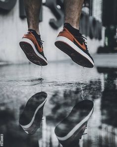 a man is jumping in the air with his shoes on and reflected in the water