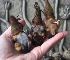 someone holding three tiny stuffed animals in their hand, one is brown and the other is green