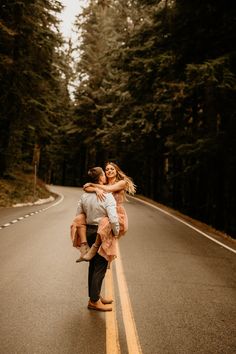 a man holding a woman on the side of a road in front of some trees