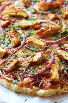 a pizza with onions, chicken and herbs on it