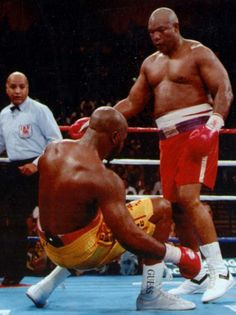 two men standing next to each other in a boxing ring with referee looking at them