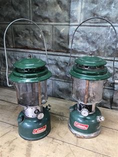 two green lanterns sitting on top of a wooden floor