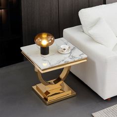 a white couch sitting next to a table with a lamp on it's end