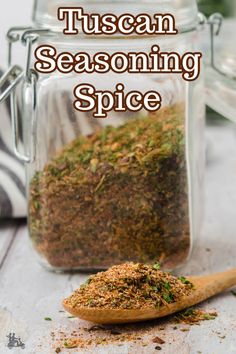 a wooden spoon filled with seasoning sitting next to a jar full of spices on top of