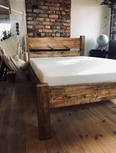 a bed frame made out of wood with a hammock hanging from the side