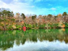 a body of water with trees in the background and a red shed sitting on top of it