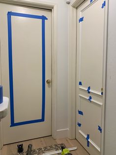 the interior of a bathroom with blue tape on the door and walls being painted white