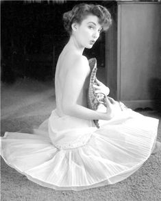 a black and white photo of a woman sitting on the floor holding a snake in her hand