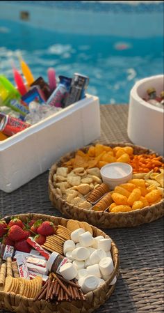 two baskets filled with snacks next to a swimming pool