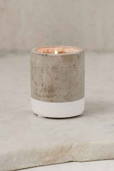 a concrete candle holder sitting on top of a white table next to a gray wall