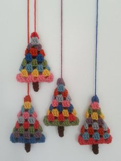 three crocheted christmas trees hanging from strings