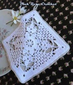 two crocheted doily on a plate next to a flower and saucer