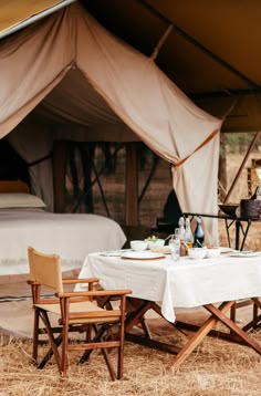 a table and chairs under a tent with a bed in the backgroung