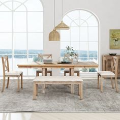 a dining room table with chairs and bench in front of large windows