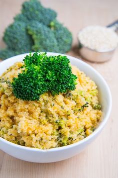 broccoli florets in a white bowl on a wooden table next to other vegetables