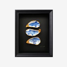 three blue and white plates in a black frame