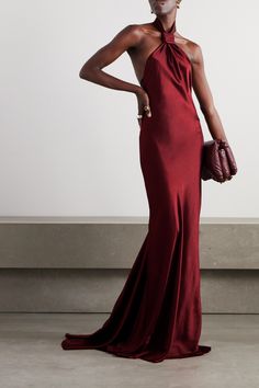 a woman in a long red dress holding a handbag and posing for the camera