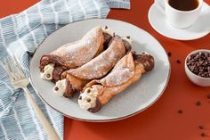 chocolate crepes on a plate next to a cup of coffee