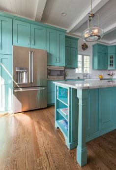 a large kitchen with blue cabinets and wood flooring, including an island in the middle