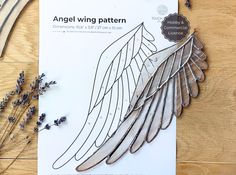 an angel wing pattern next to some lavenders on a wooden table with scissors and thread