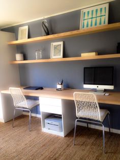 a desk with two chairs and a computer monitor on it in a room that has carpeted flooring