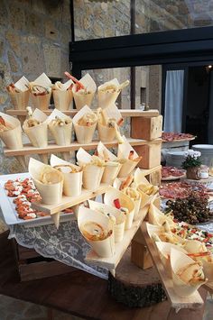 a table topped with lots of food on top of wooden trays next to a stone wall