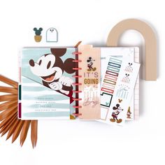 an open notebook with mickey mouse on it and other items in front of the book