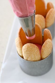 a person is pouring something into a cup filled with oranges and powdered sugar