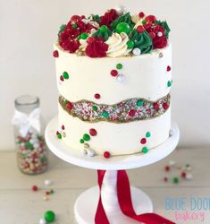 a white cake with red and green sprinkles sitting on top of a table